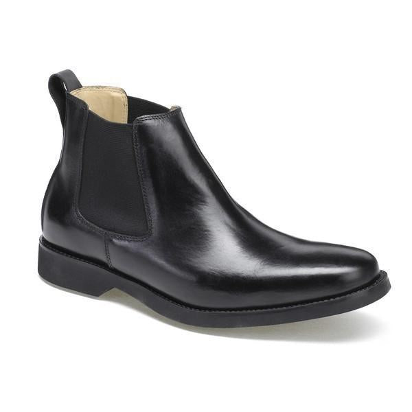 The sleek, black leather upper is prominently displayed, showcasing the smooth texture and polished finish. The round toe shape and clean stitching along the seams highlight the boot’s classic design. The ankle height and subtle 2cm heel-platform provide a balanced silhouette.