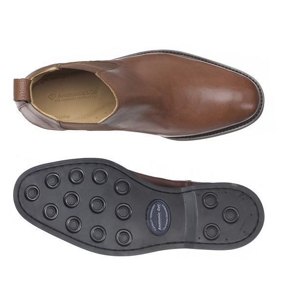A top-down view of the Anatomic Cardoso Pinhao Ankle Boots, with one boot turned upside down to reveal the Anatomic Gel Technology® sole. The image highlights the detailed design of the non-slip, gel-infused sole and the soft leather upper, demonstrating the boot's comfort and functionality.