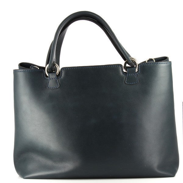The Bridas 857 Blue Handbag is showcased on a clean, neutral background, allowing its deep blue leather to stand out. The bag has a structured, rectangular shape, emphasizing its spacious design. An adjustable strap is displayed beside it, illustrating its versatility. The leather's texture is highlighted, showing the fine grain and quality. The photo also captures the stitching details, reflecting the handcrafted artistry that Bridas is known for. 