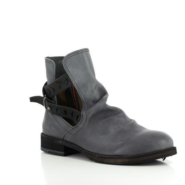 A dynamic angled shot of the boot highlighting the smooth curves of the leather upper and the layered design of the black strap and buckle. The subtle shine of the buckle contrasts beautifully with the matte leather texture, while the slight heel is visible, emphasizing its practical yet chic design.