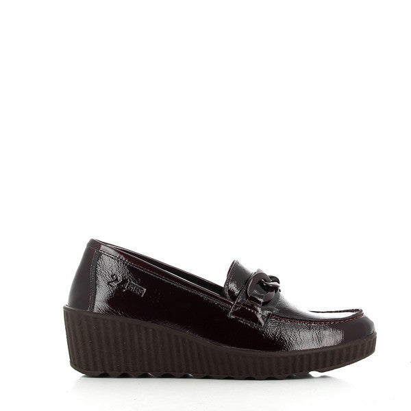 A close-up shot of the 24HRS 23801 Burgundy Loafers, showcasing their premium leather upper with a smooth, polished finish. The round toe shape is clearly visible, along with the 5 cm heel-platform that adds subtle height. The deep burgundy color gives the loafers a rich, elegant appearance. The photo highlights the craftsmanship and attention to detail, with the stitching along the edges and the sleek, synthetic sole that promises comfort and durability. The background is neutral, allowing the burgundy loa