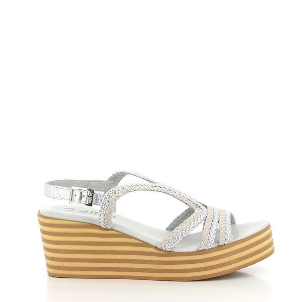 A pair of 24 Hrs 24105 Silver Slingback Wedges is showcased on a neutral background. The wedges feature a sparkling silver leather upper with a round toe and an elegant slingback design. The 5.5 cm heel adds a stylish lift, while the durable synthetic sole ensures stability. The soft leather lining is subtly visible from the top, highlighting comfort and high-quality craftsmanship. The overall design combines glamour with practicality, making these wedges a versatile addition to any wardrobe.