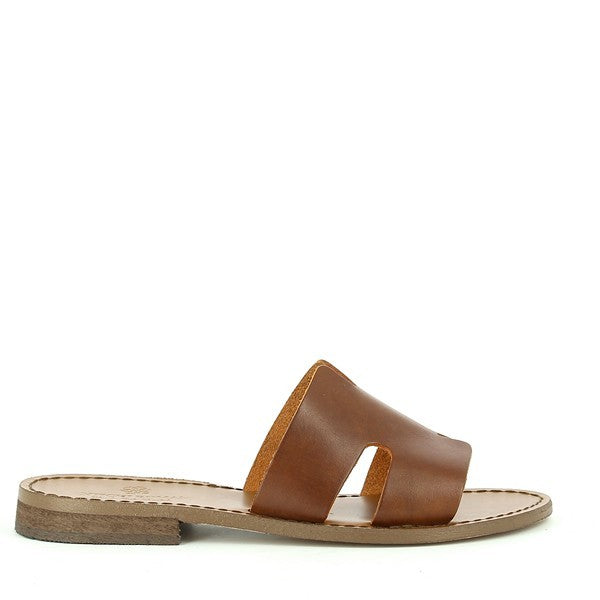 The Antichi Romani 01 Nuovo Cuoio Brown Slides are showcased with their rich brown leather upper, exuding classic elegance. The slides feature a minimalist design with a 1cm heel-platform height and a round toe shape for a timeless look. The soft leather lining and sole are visible, emphasizing the craftsmanship and comfort. Set against a neutral background, the slides highlight their luxurious material and expert Italian craftsmanship.