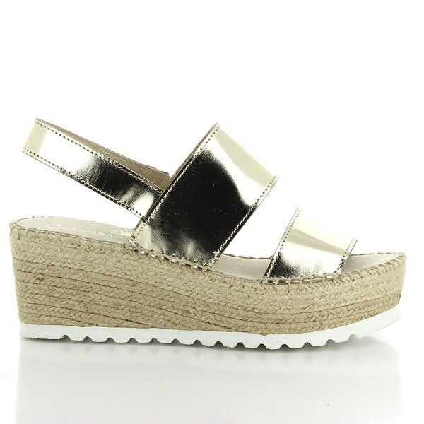 The image showcases a pair of Calzanor 1937 Gold Slingback Espadrilles, elegantly positioned on a soft, neutral background. The shimmering gold leather upper catches the light, radiating a sophisticated allure. The handcrafted details are evident in the precise stitching, reflecting the artisanal craftsmanship that has been honed over 30 years. The comfortable 7cm jute platform heel is prominently featured, adding a stylish lift while the classic round toe shape enhances the espadrille’s timeless elegance. 