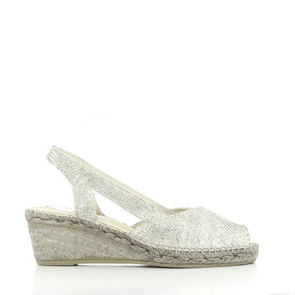 A pair of Calzanor 2047 Silver Slingback Espadrilles is beautifully displayed against a soft, neutral backdrop. The shimmering silver leather upper catches the light, adding a sophisticated shine. The slingback strap is elegantly designed for a secure fit, and the rounded toe shape gives the espadrilles a classic, comfortable look. The 6 cm jute platform sole, meticulously hand-stitched, showcases the natural, eco-friendly material. 