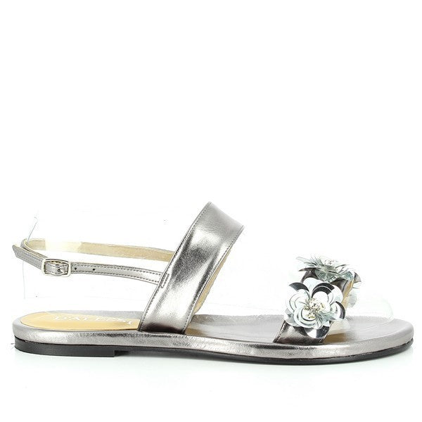 A pair of Dalessi Dakota Pewter Slingback Sandals showcased on a neutral background. The sandals have a sleek, metallic pewter synthetic upper, accented with delicate floral details along the strap, adding a feminine charm. The rounded toe and 1.5cm platform heel offer a refined yet comfortable look. The soft leather lining is visible, enhancing the luxurious feel, while the sturdy synthetic sole ensures stability. The slingback strap provides a secure, stylish fit.