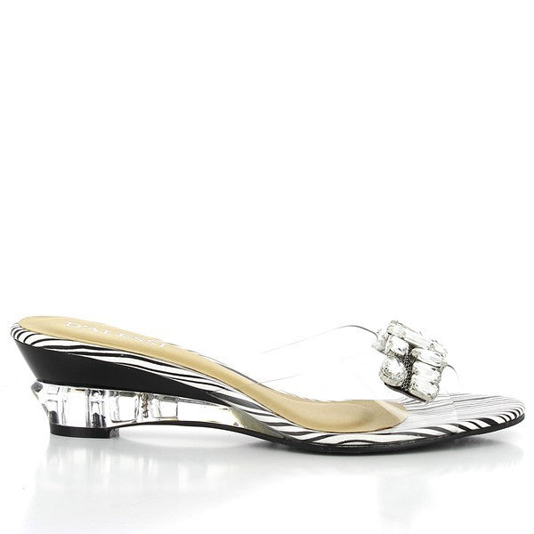 The Dalessi Delicia Black & White Slides are shown from a side angle, highlighting the modern black and white color contrast on the upper straps. The synthetic upper features a smooth finish, while the soft leather lining is slightly visible, promising comfort. The 5 cm platform heel offers a stylish lift, and the round toe shape provides a relaxed fit. The synthetic sole, visible from the base, is designed for durability and support. 

