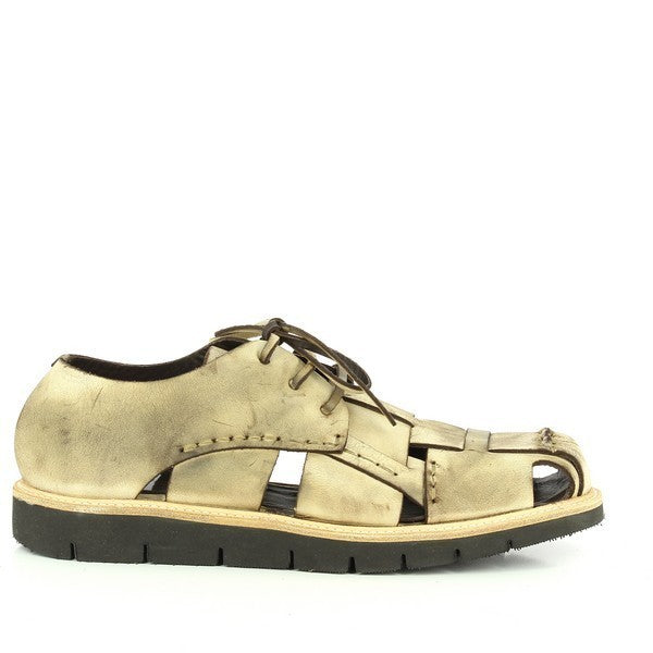 A beige lace-up shoe with a sleek leather upper featuring stylish open spaces on the sides, resembling a sandal. The round toe and clean stitching highlight its refined craftsmanship, while the synthetic sole offers a slight 2.5cm heel for subtle elevation.