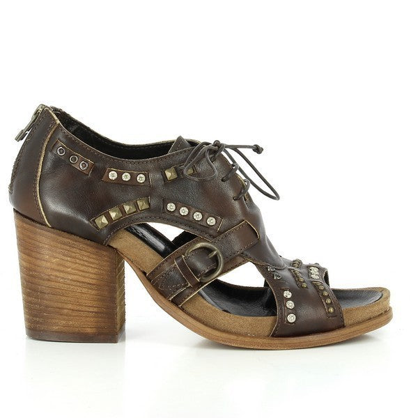 A full side profile of the bootie showcasing the smooth brown leather upper with intricate cut-out details, decorative golden studs, and a 7cm leather-wrapped heel.