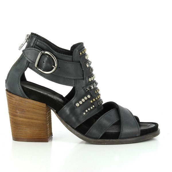 A side profile of the sandal, showcasing the sleek black leather upper, front cross-straps, and 7cm leather-wrapped heel, with decorative golden studs and buckle detail.