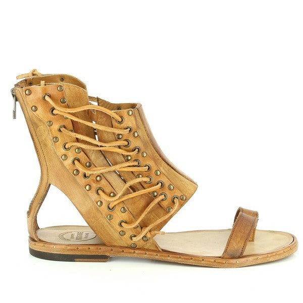 A clean side profile showcasing the sandal’s elegant tan leather construction, open sides, and intricate lace-up details that run along the side straps.