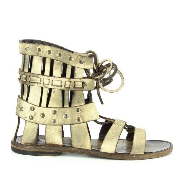 A sleek Roman-style sandal in metallic gold leather, showcasing thin, elegant straps that create a timeless and airy design. The 1cm sole adds a subtle lift, highlighting the blend of style and comfort.