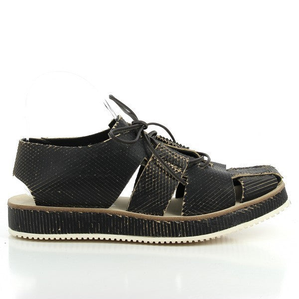 A side view of the Forte S17-4264 Black Cage Sandals, showcasing the intricate leather straps that form the cage design, adding a modern and stylish edge to the overall look. The sandal's rounded toe and low heel provide both comfort and sophistication.

