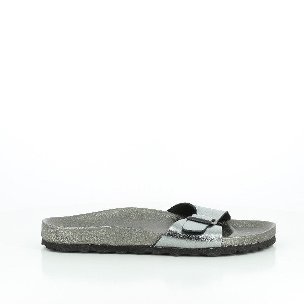 A close-up image showcasing Plakton's 261625 Silver Single-Strap Sandals. The sandals feature a sleek, metallic silver leather strap that elegantly wraps across the foot. The cork sole, combined with synthetic materials, provides support and flexibility. With a 2cm heel-platform and a round toe shape, these women's slides are designed for both style and comfort. Crafted in Spain, these sandals highlight superior craftsmanship and minimalist design, perfect for any casual or chic ensemble.